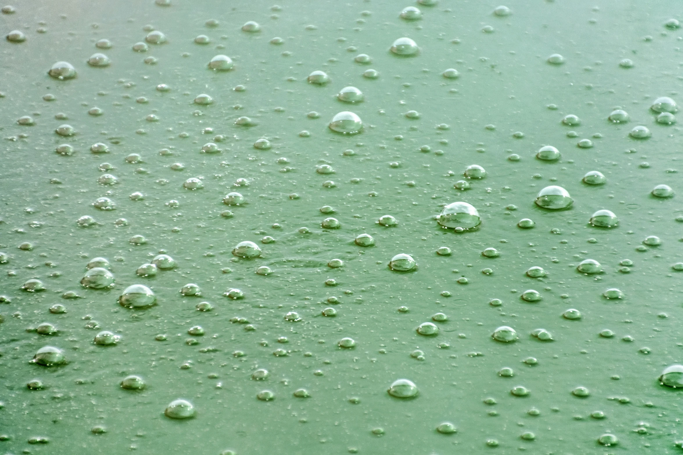 water droplets are shown on the surface of a blue and green liquid