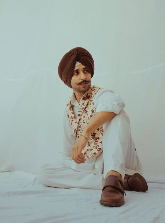 a man sitting on a bed wearing a turban