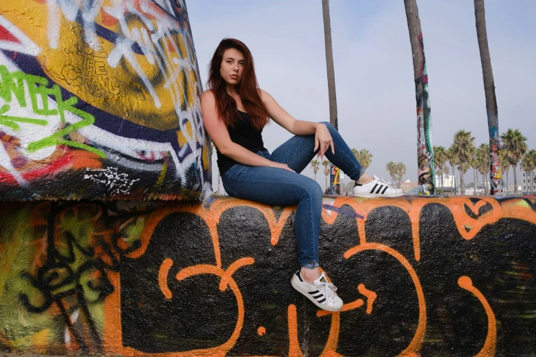 a woman sitting on a wall with graffiti on it