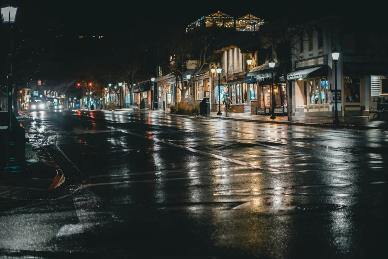 an empty street at night with wet sidewalks and lights