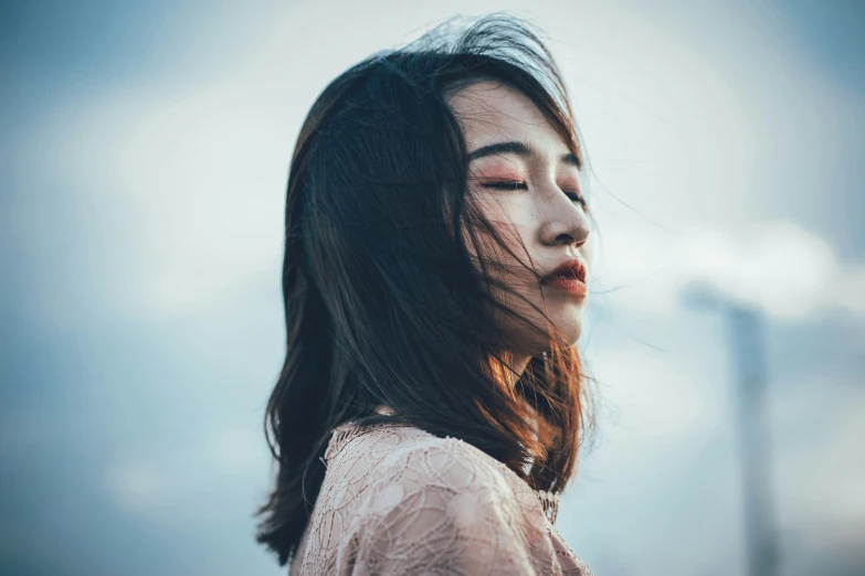 a woman with long hair standing on a cloudy day