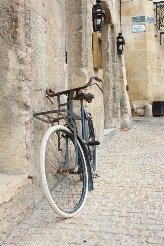 a blue bike sits on a cobblestone road next to an old building