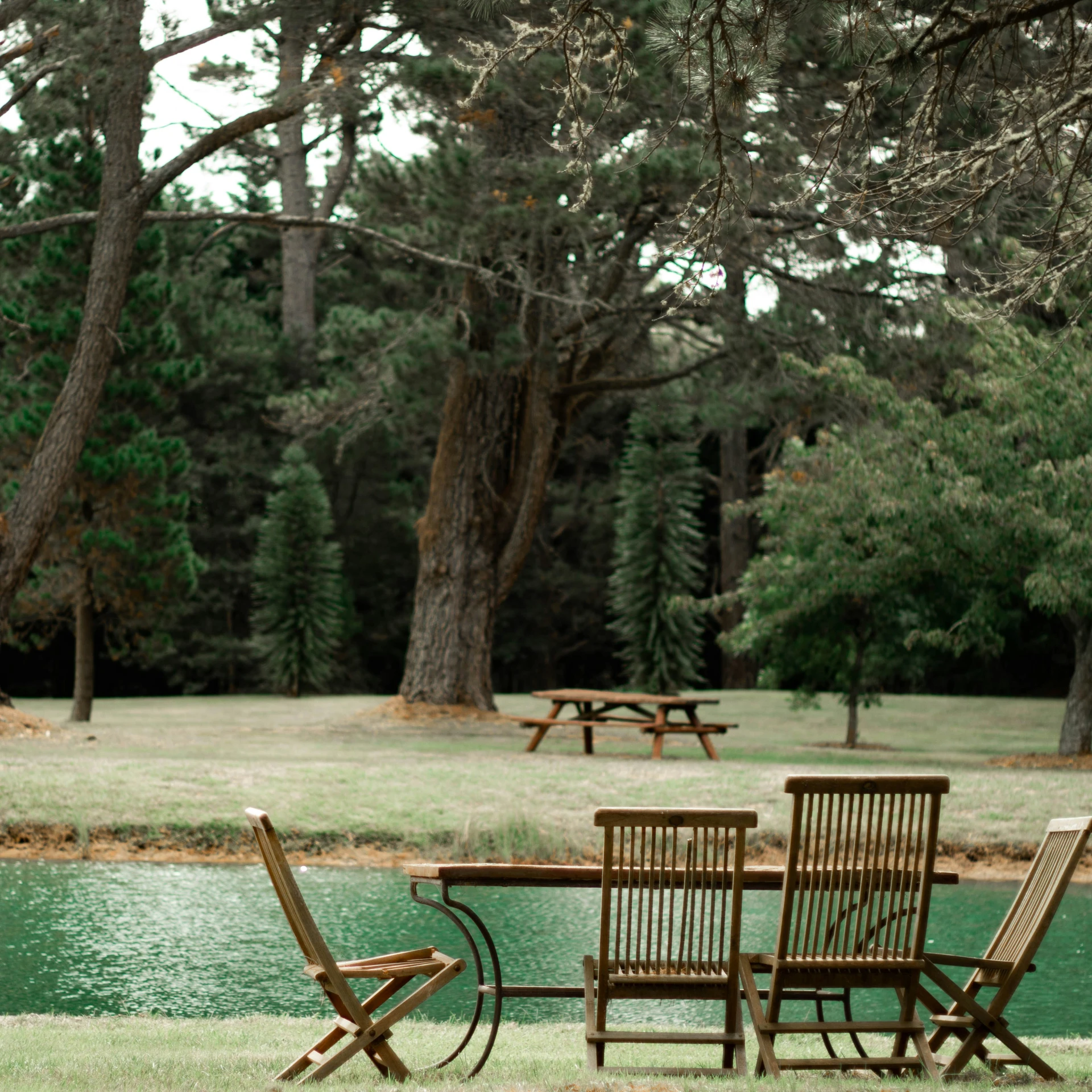 there are lawn chairs with a table in the park