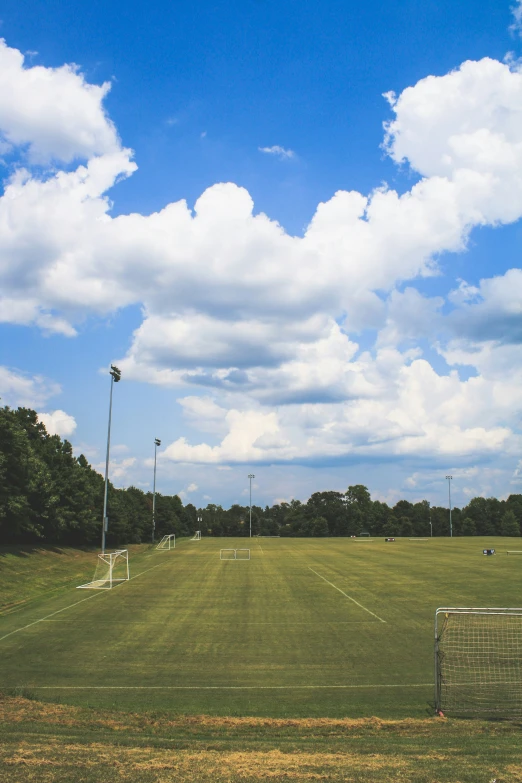 a soccer field under a blue sky with some clouds