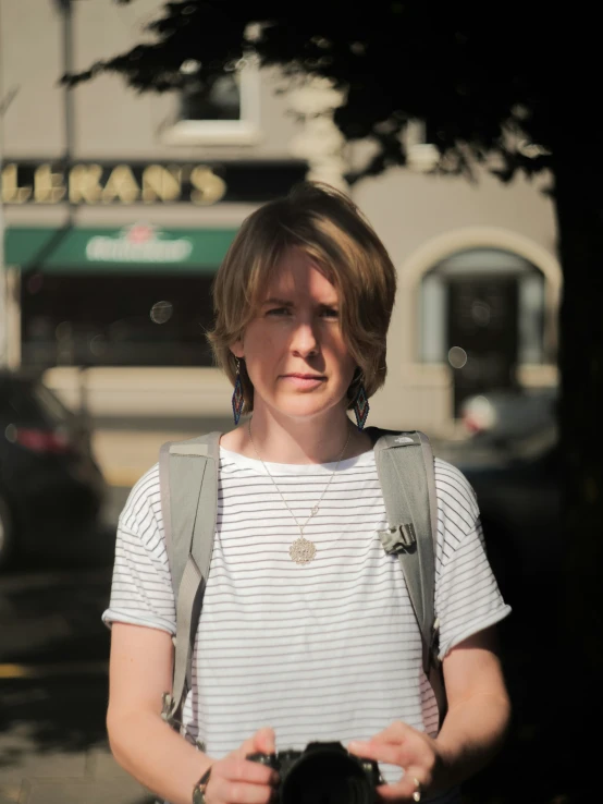 a young woman holding up her camera with another woman walking past