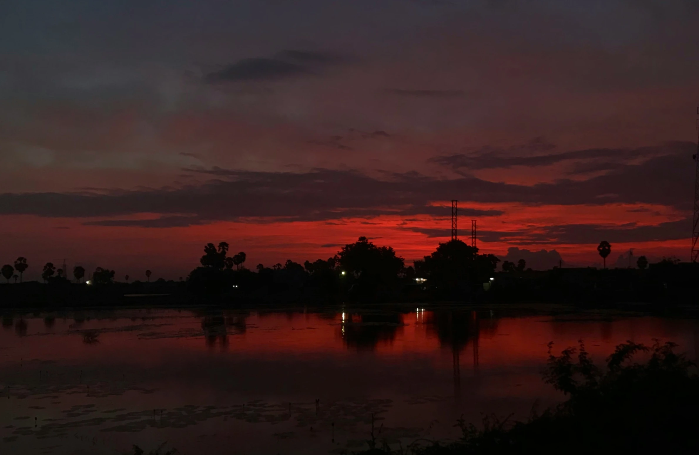 a body of water with a red sky in the background