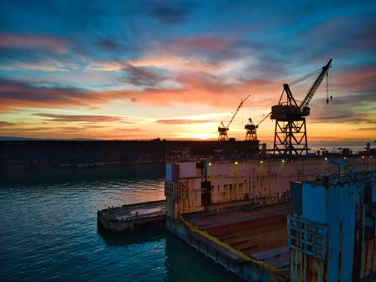 the sun sets behind an old, crumbling ship