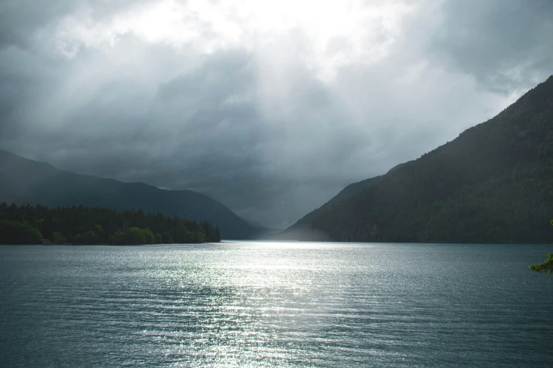 dark and stormy skies surround the mountains along the water