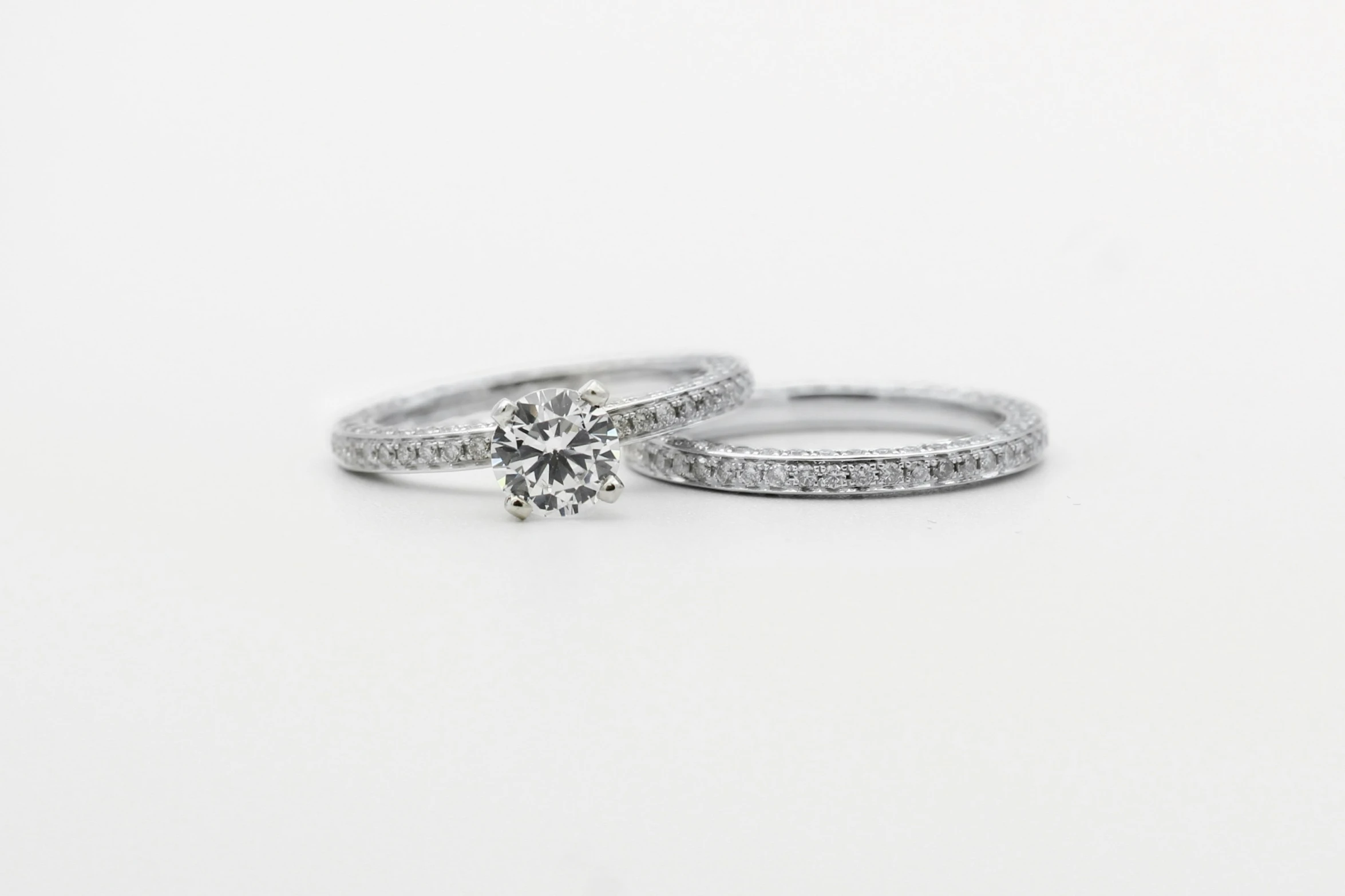 a pair of engagement and wedding rings sitting on top of a white table