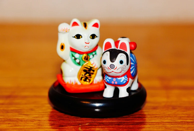 two small ceramic figurines of cats standing on one another