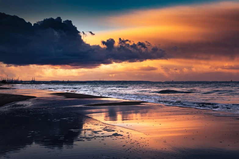 a sun peeks from behind storm clouds as it rises over a beach