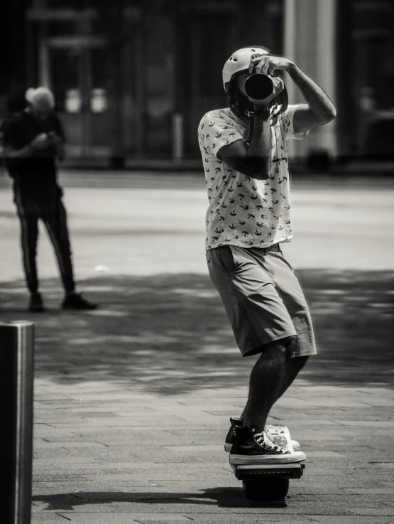 man skateboarding on the sidewalk while another man takes a picture