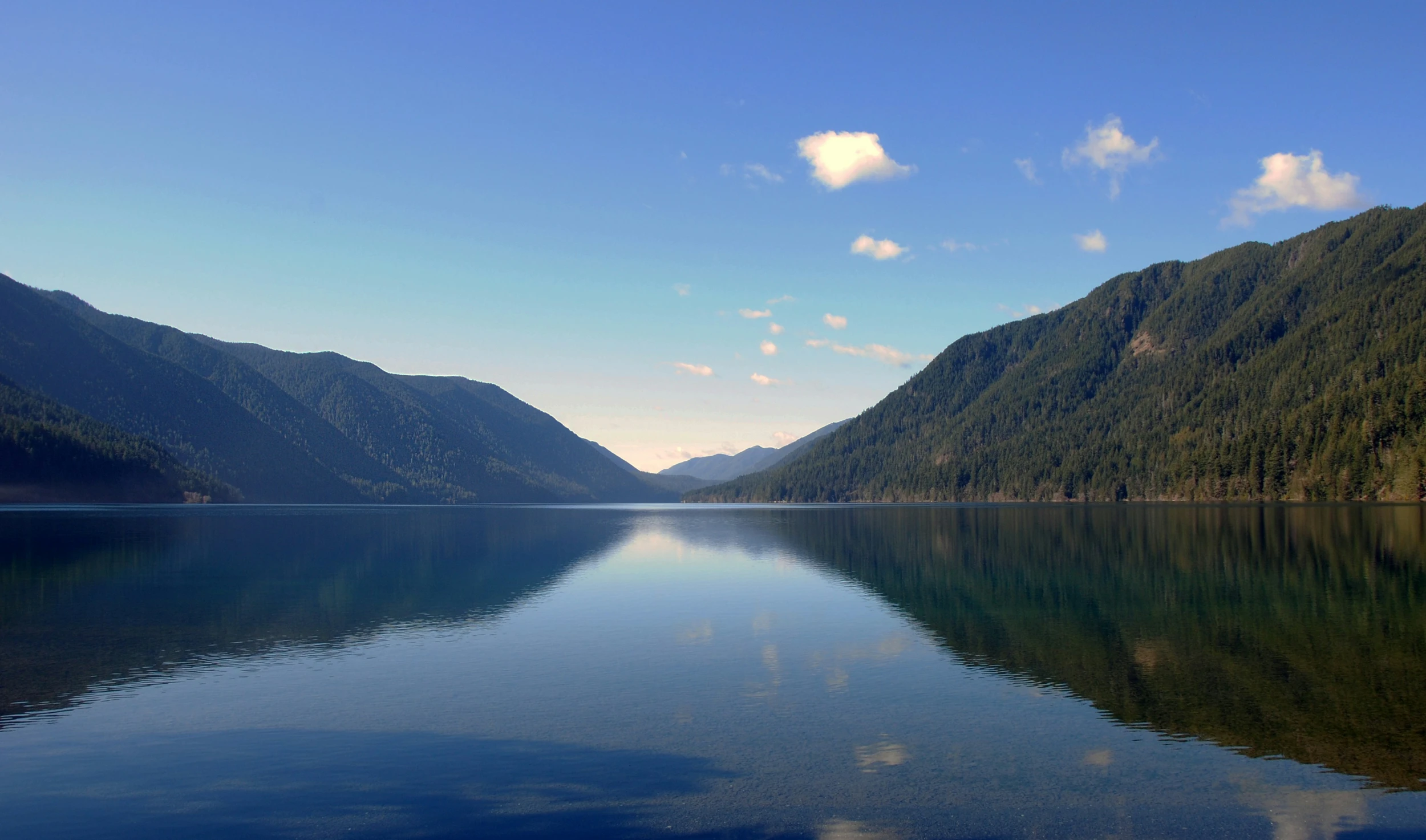 this is a lake surrounded by mountains under a blue sky