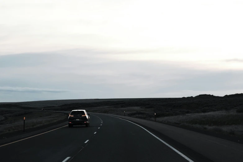 a black truck is driving on a highway in a field