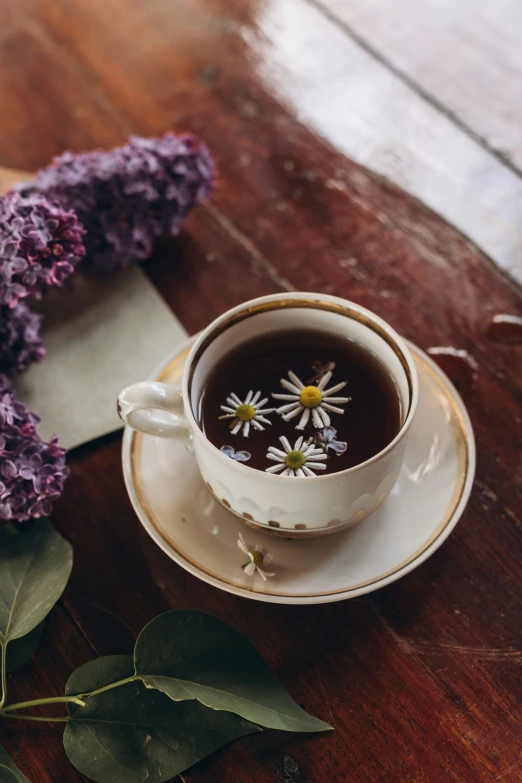 a cup of tea with daisies in it and a piece of paper