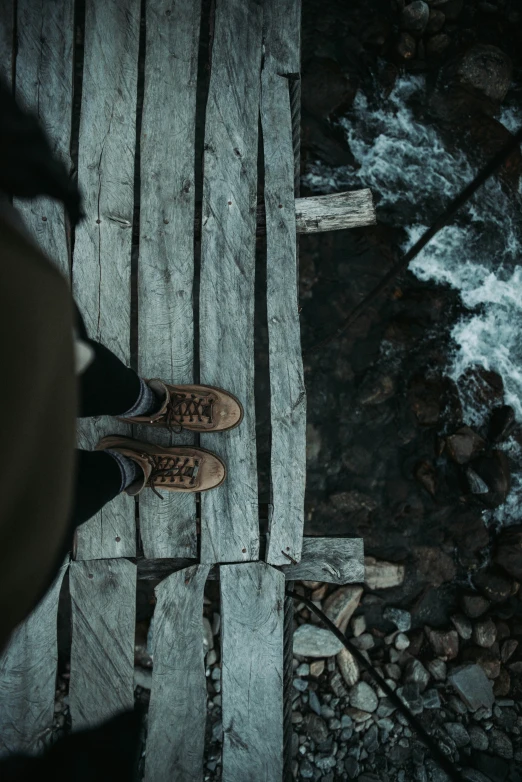 view from above of shoes and river on wooden walkway