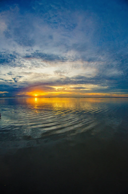 sunset over water with horizon in foreground with small boat sailing