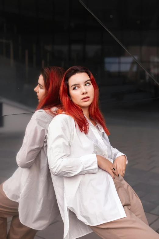 a red haired woman sits down with her hands behind her back