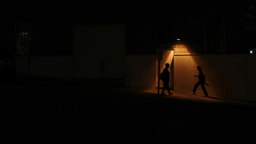 two people are walking down the street in the dark