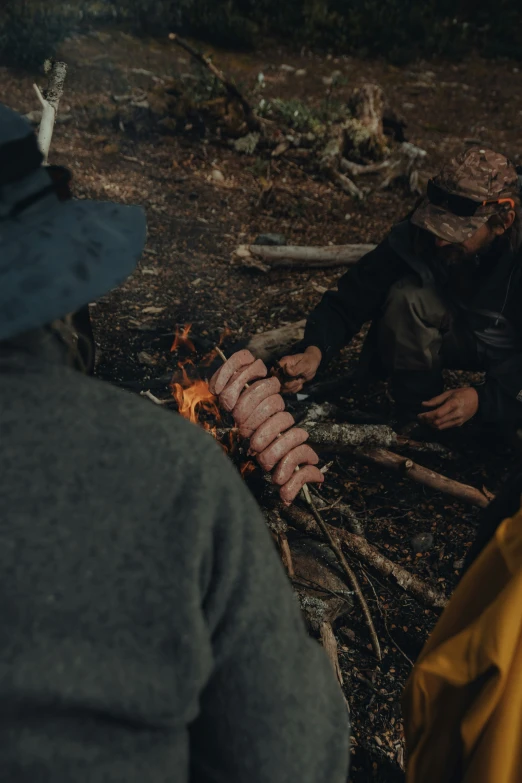 two people are roasting soing on a stick in the woods