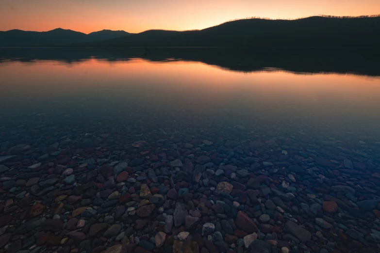 a view from the shore at dusk of a rocky lake