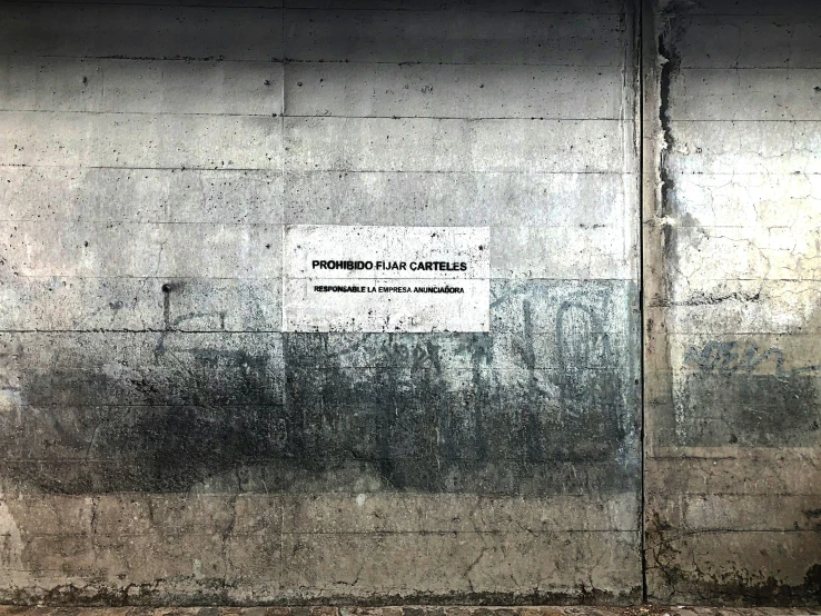 a concrete wall with a white sign that says