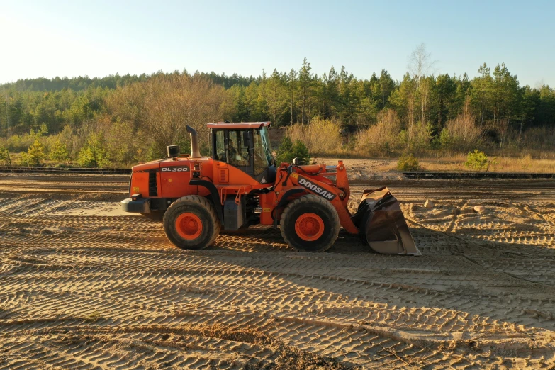 an orange tractor parked on the side of a dirt road