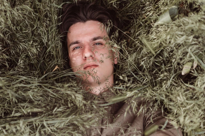 a young man in a green grass bush