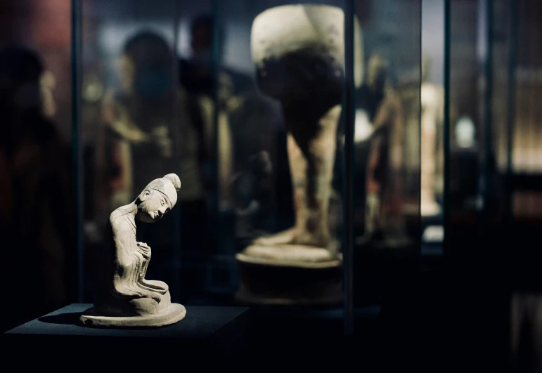 a statue of a female standing on a platform and reflecting in glass cases