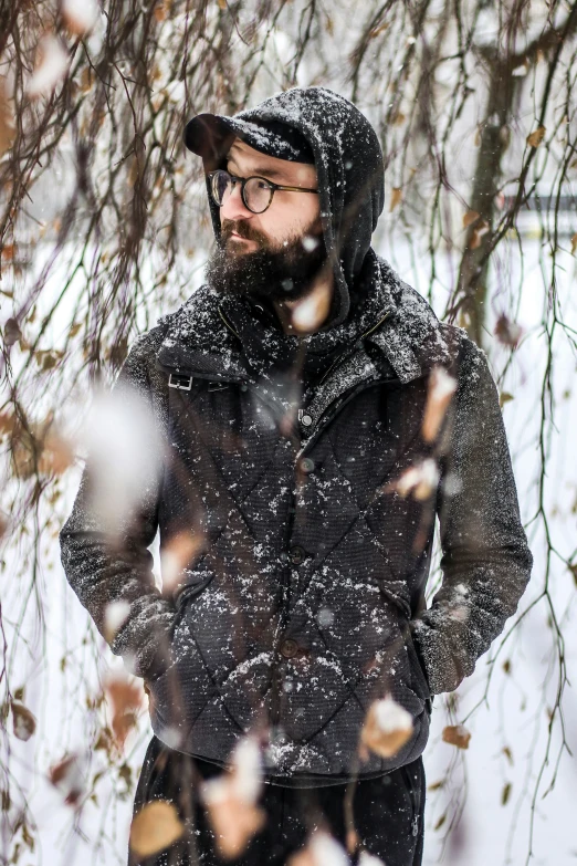 a man in a winter jacket and cap standing by some snow