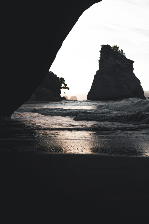 an arch is seen from the beach next to the ocean