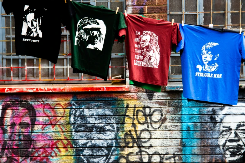 t - shirts hung up against a fence on a street