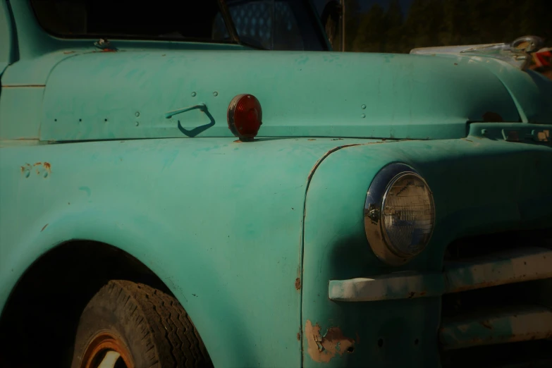 the front end of an old, dusty green truck
