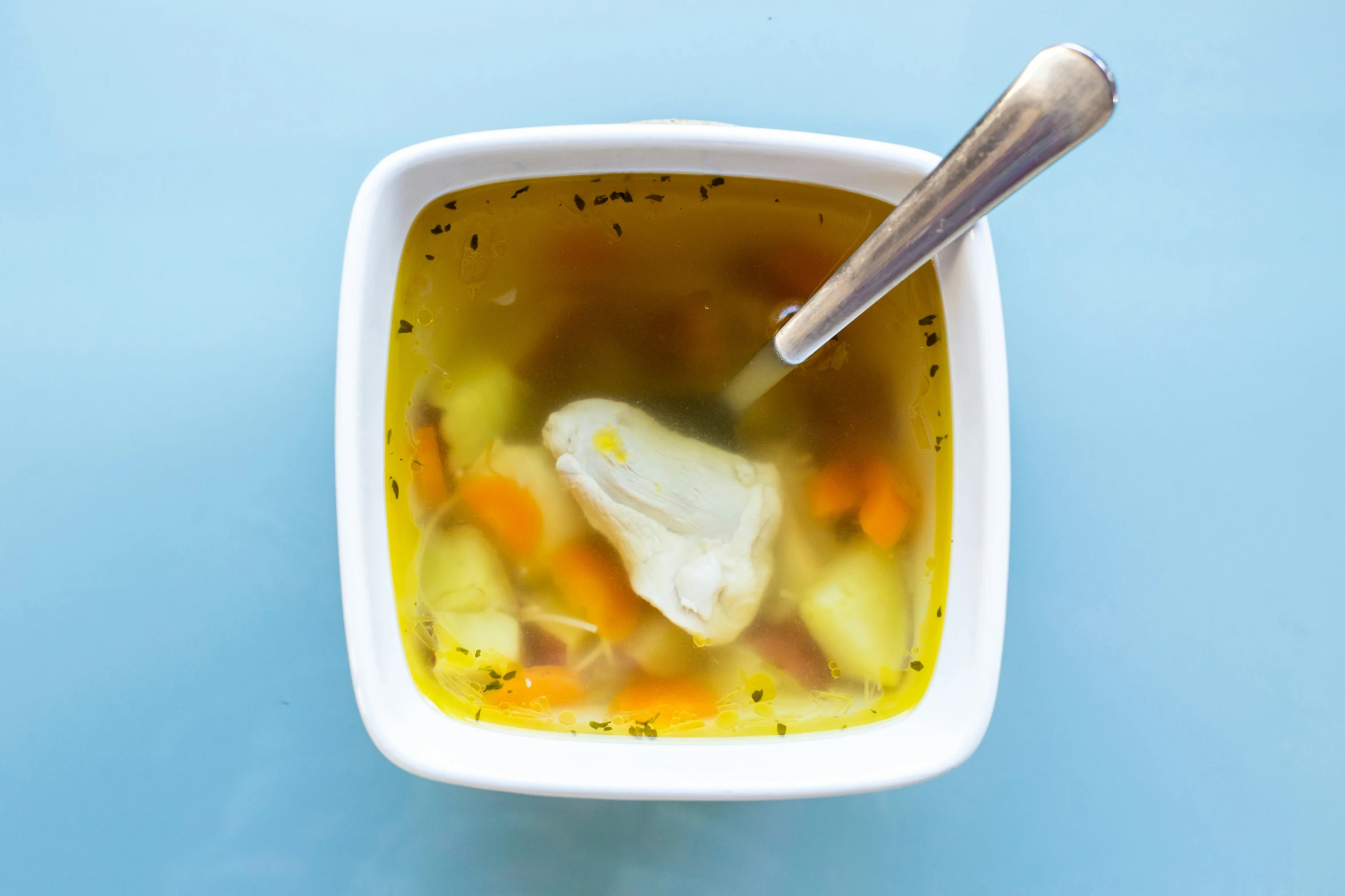 a spoon in a bowl of soup that includes vegetables