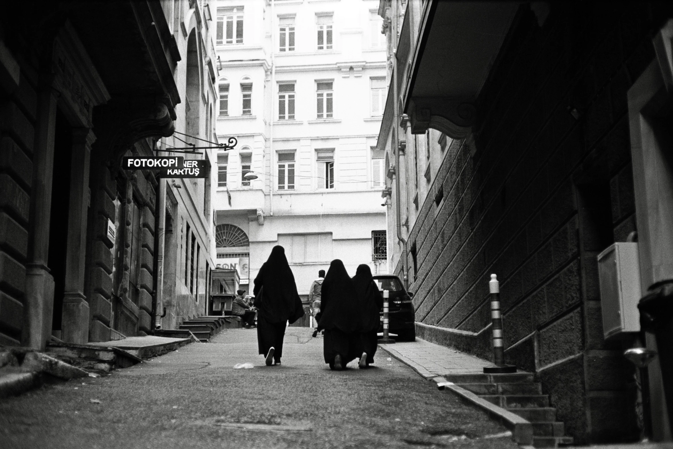 three women walking down a narrow street on their back