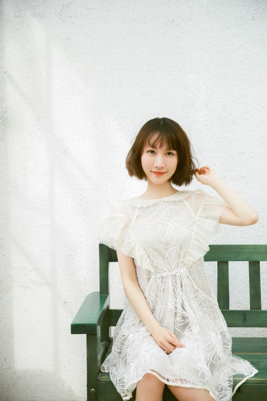 the young woman is sitting on the green bench