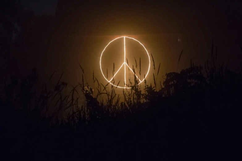 a peace sign made of light is sitting in the dark
