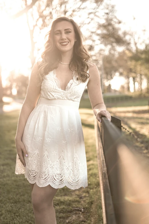 a woman in a white dress standing near a rail