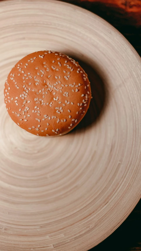 a small sesame seed burger on top of a round white plate