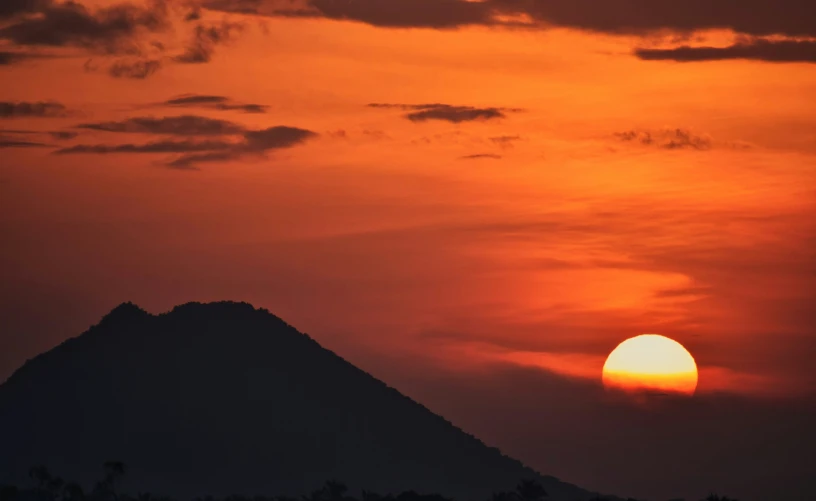 the sun sets over a mountain and a small airplane