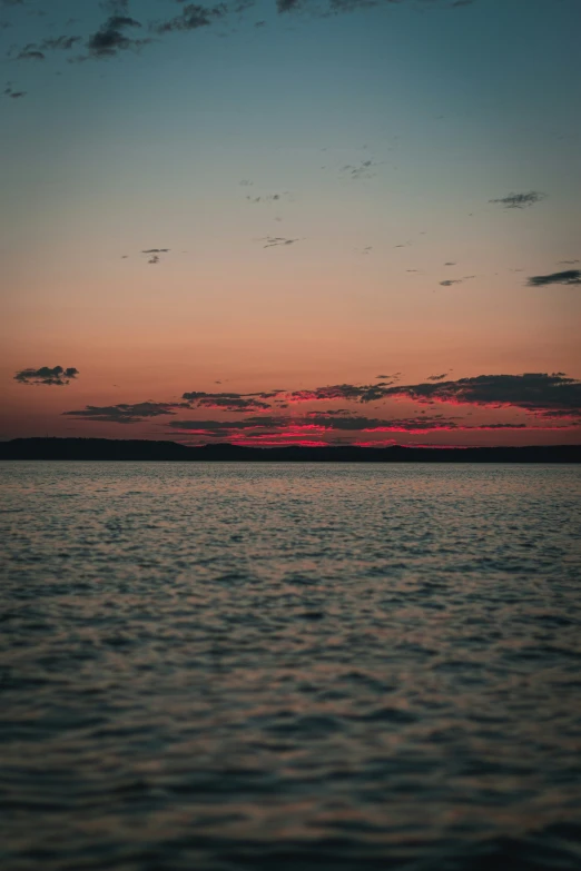 a lone ship sails past the sun set