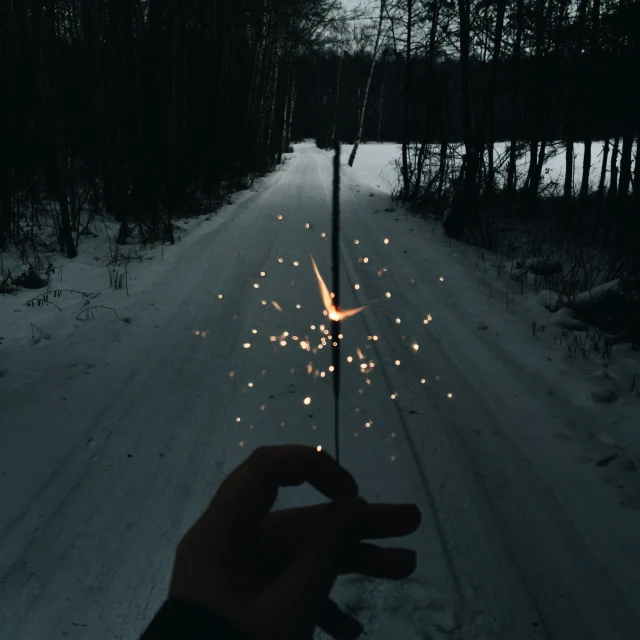 hand pointing at fireworks lite on road at night