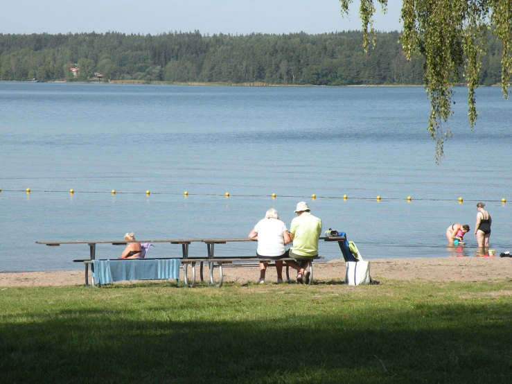 a group of people sitting at a picnic bench looking out over the water