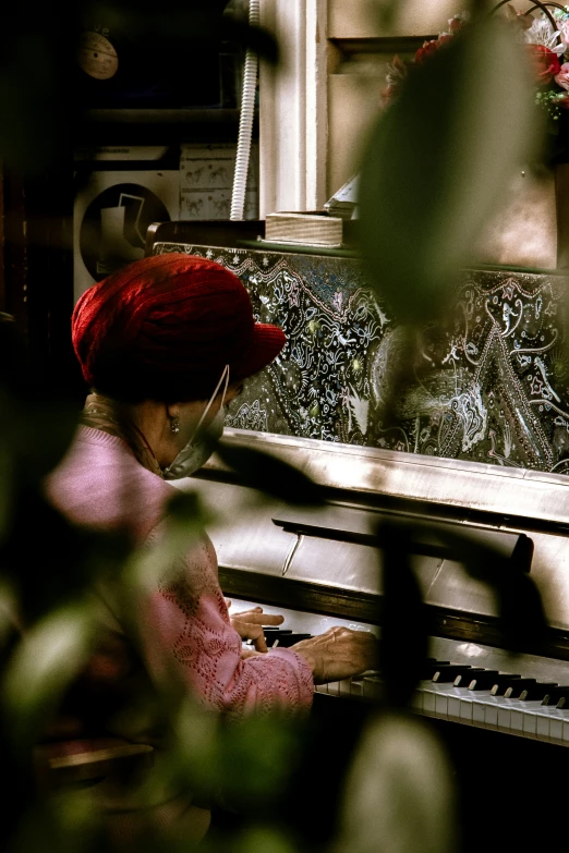woman in red turban playing piano on street