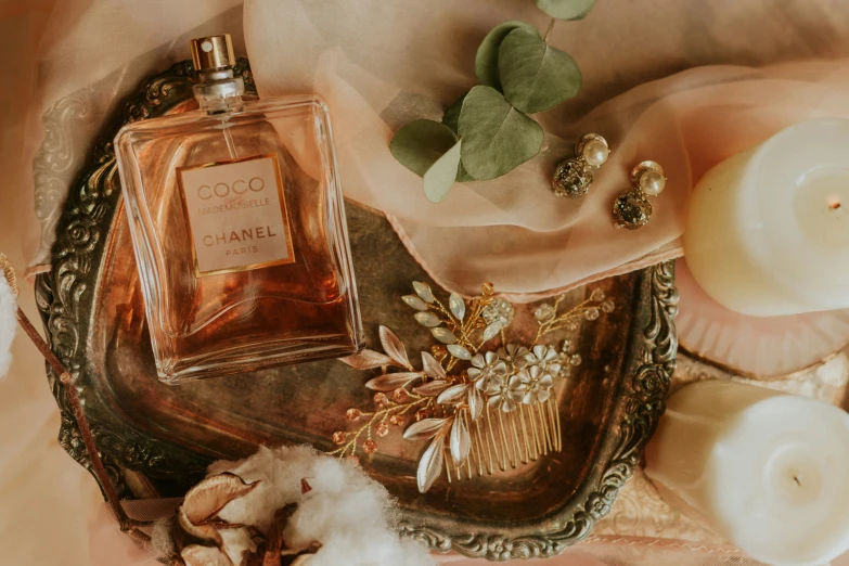 an antique perfume bottle surrounded by flowers, candles and some cotton