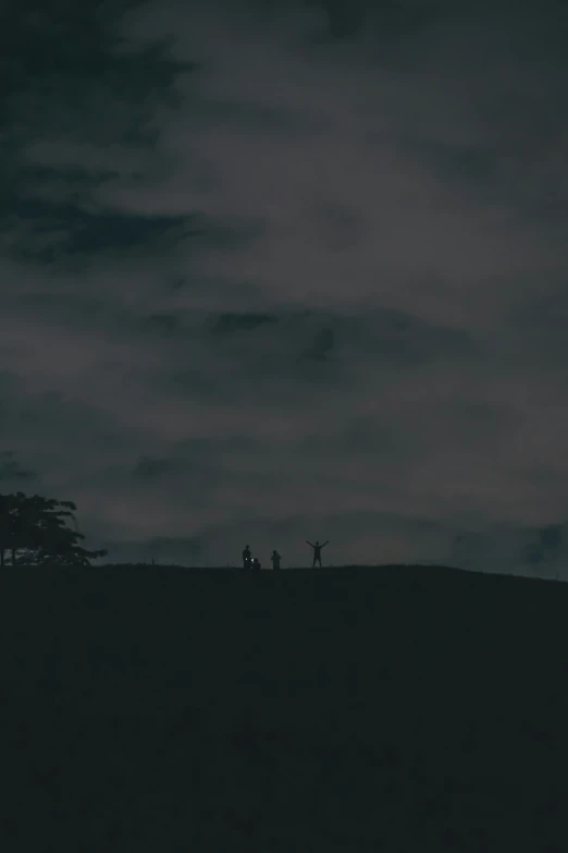 the clouds are lit up and people walking on the hill