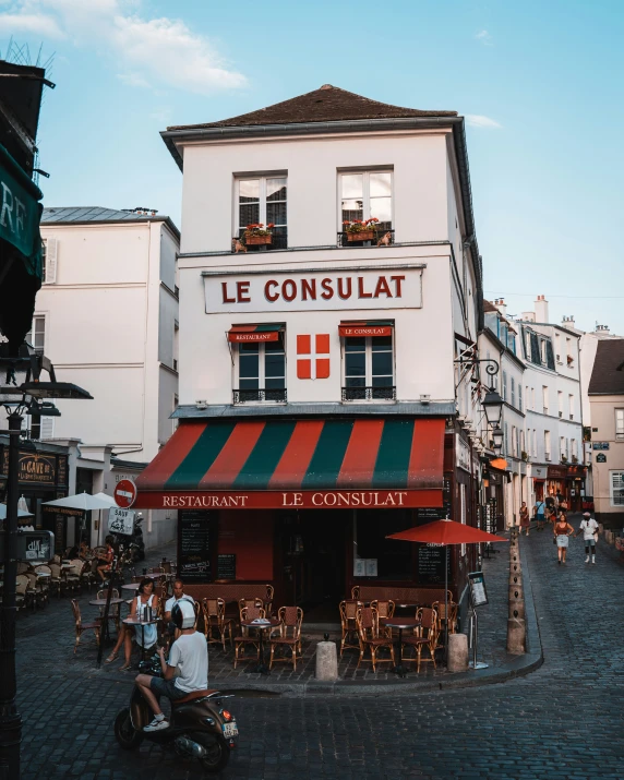 a store with red and green awning and people outside it