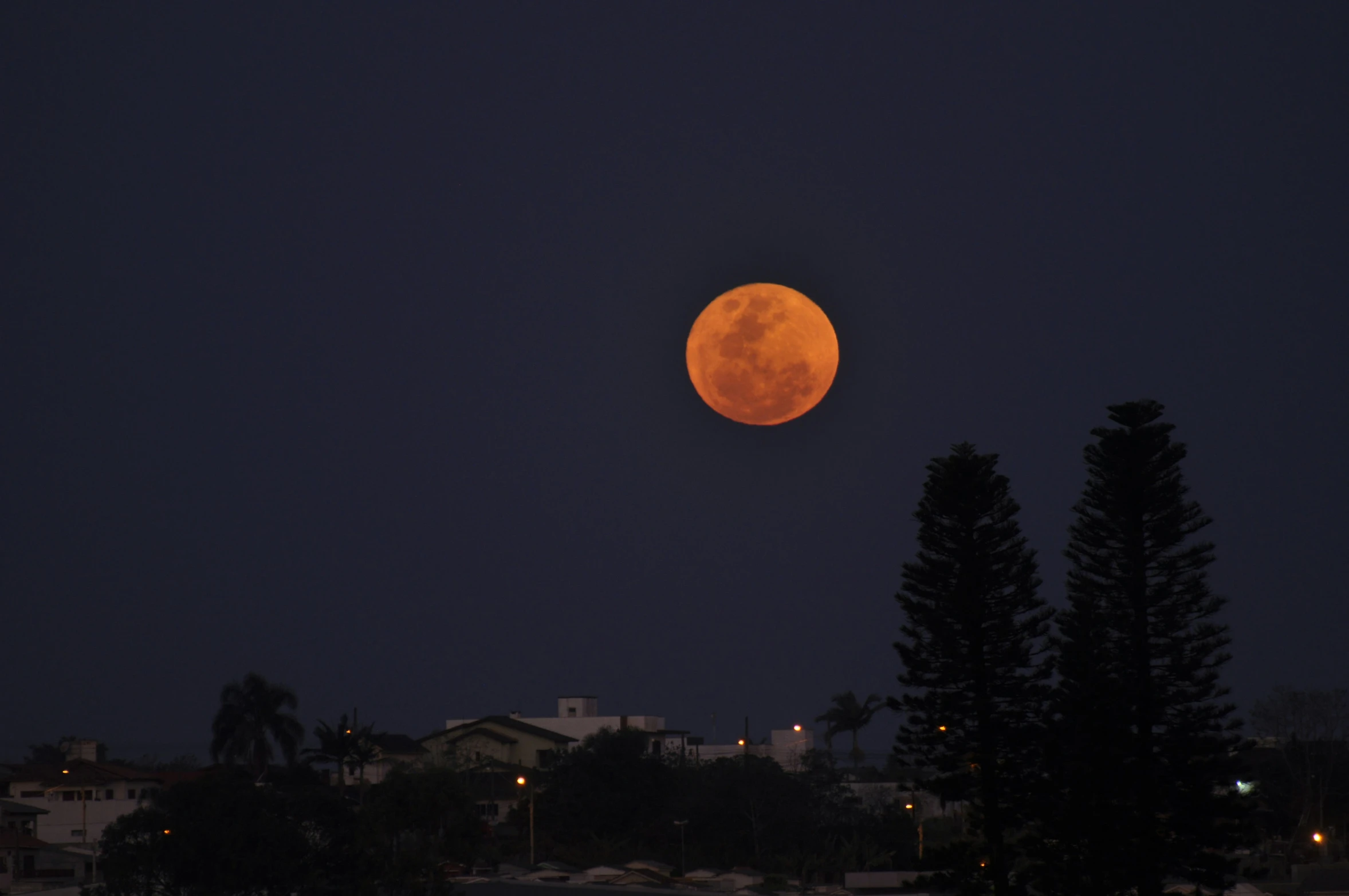 a full moon rises above a small town