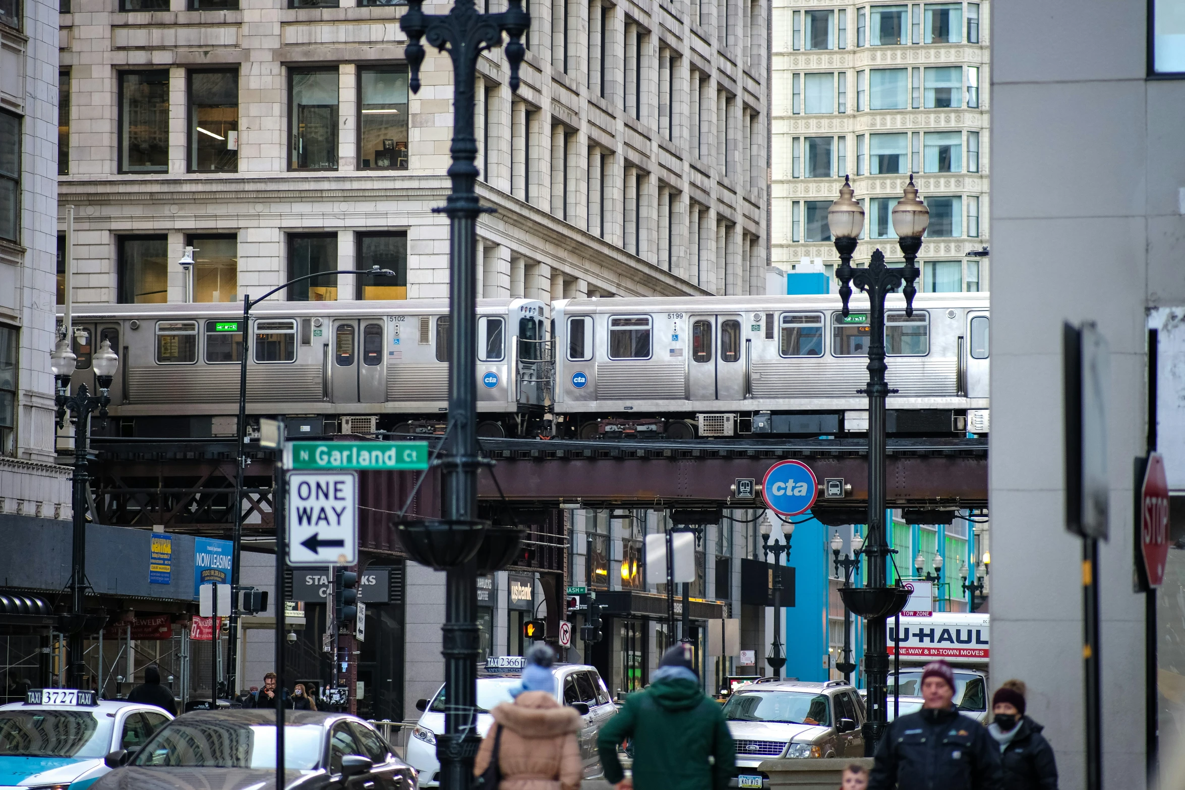 people are walking along the sidewalk near a commuter train