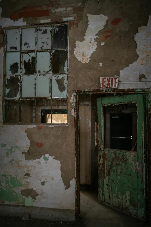 an old and rusted hallway with a green door and exit sign